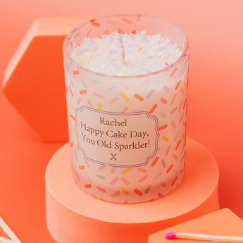 Sweet Celebration Birthday Cake Candle in a frosted clear glass jar, featuring a sprinkles pattern with a birthday message. Made with soy wax and a delicious cake scent – perfect for gifting.