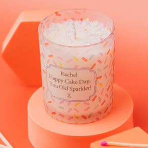 Sweet Celebration Birthday Cake Candle in a frosted clear glass jar, featuring a sprinkles pattern with a birthday message. Made with soy wax and a delicious cake scent – perfect for gifting.